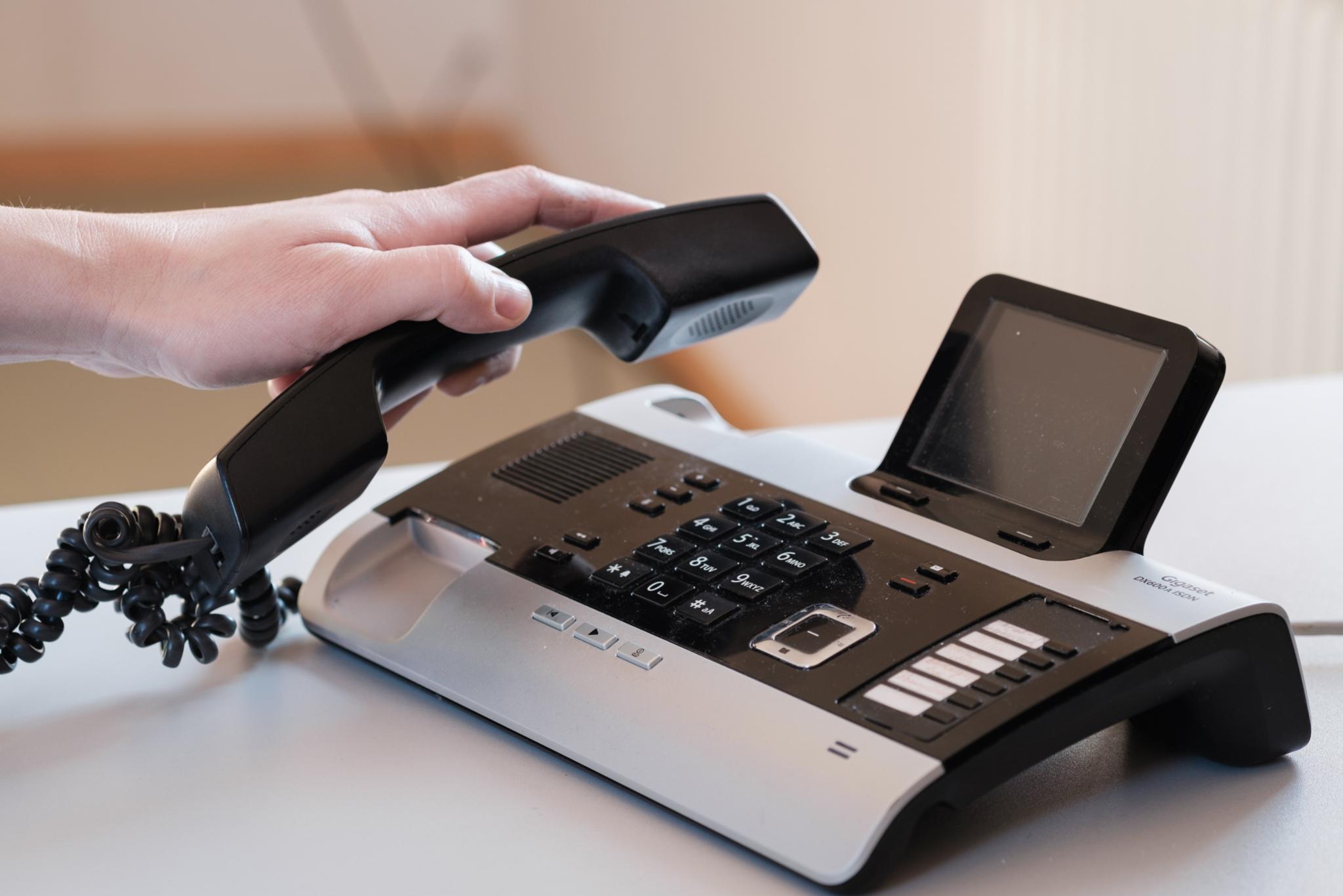 Hand hebt Telefonhörer an